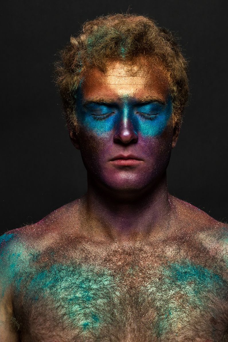 Creative beauty portrait featuring turquoise and pink face paint against dark background.