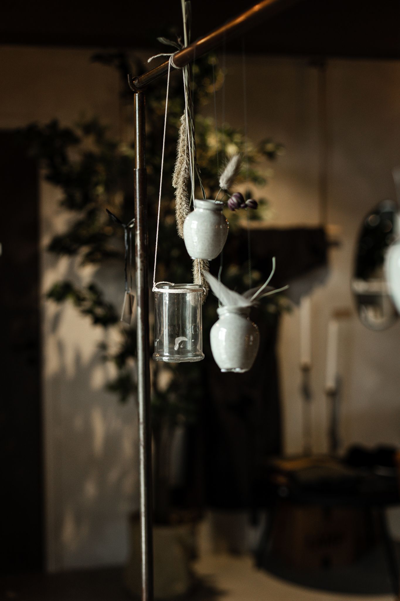 Hanging decorative ceramic planters and glass lanterns creating moody interior ambiance.