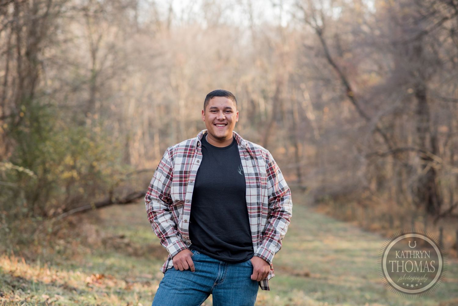 Casual outdoor portrait of someone wearing plaid flannel against fall foliage background.