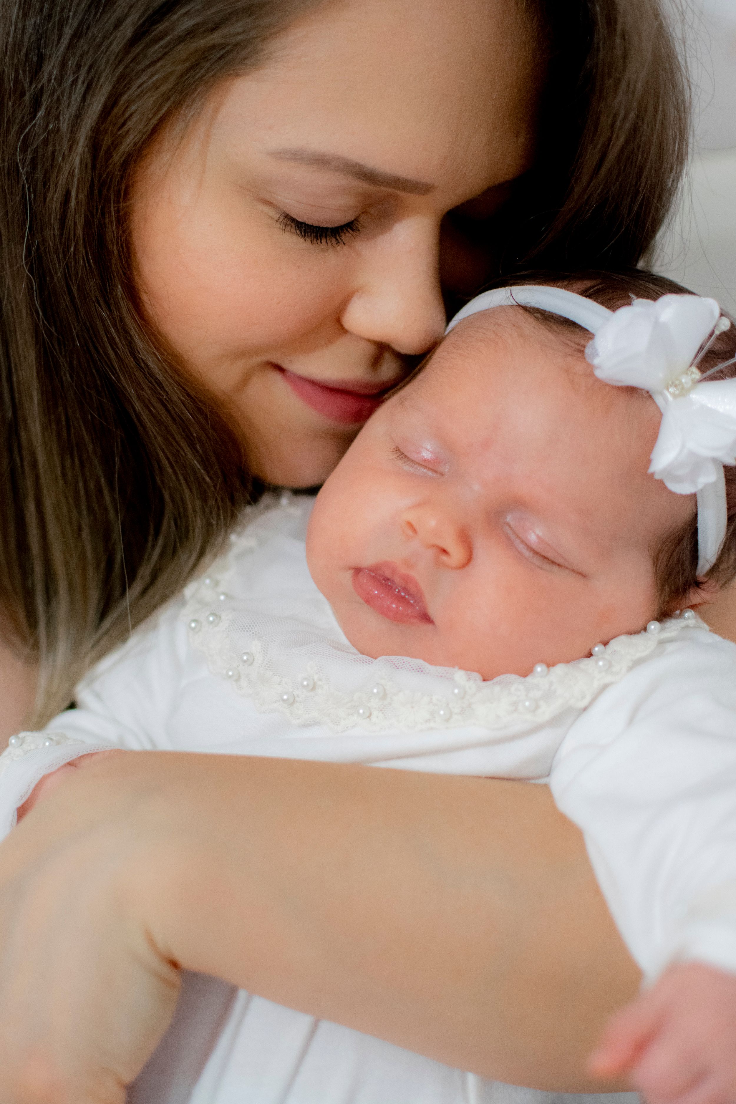 Tender moment between parent and infant dressed in white.