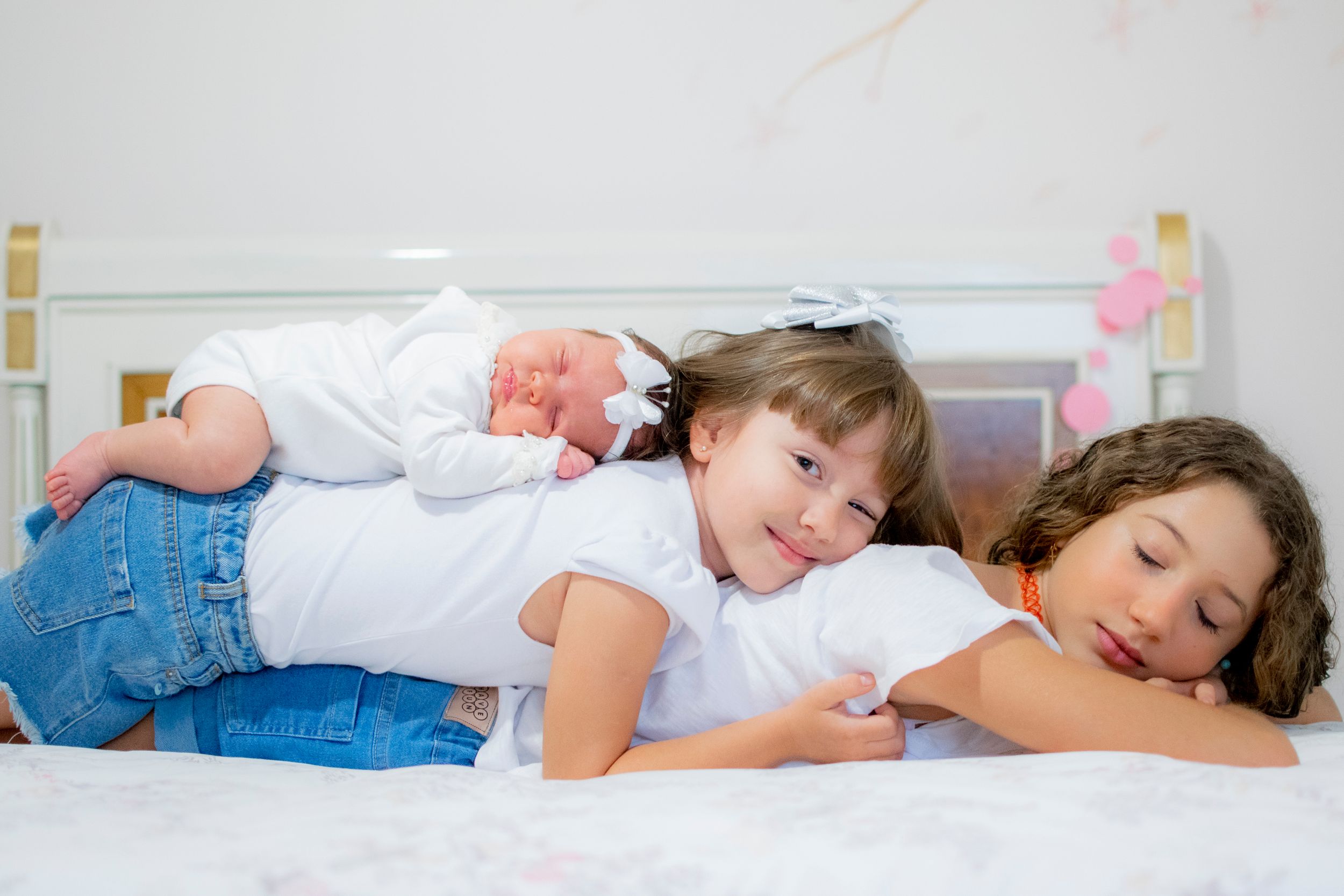 Three people laying together relaxed on white bedding.