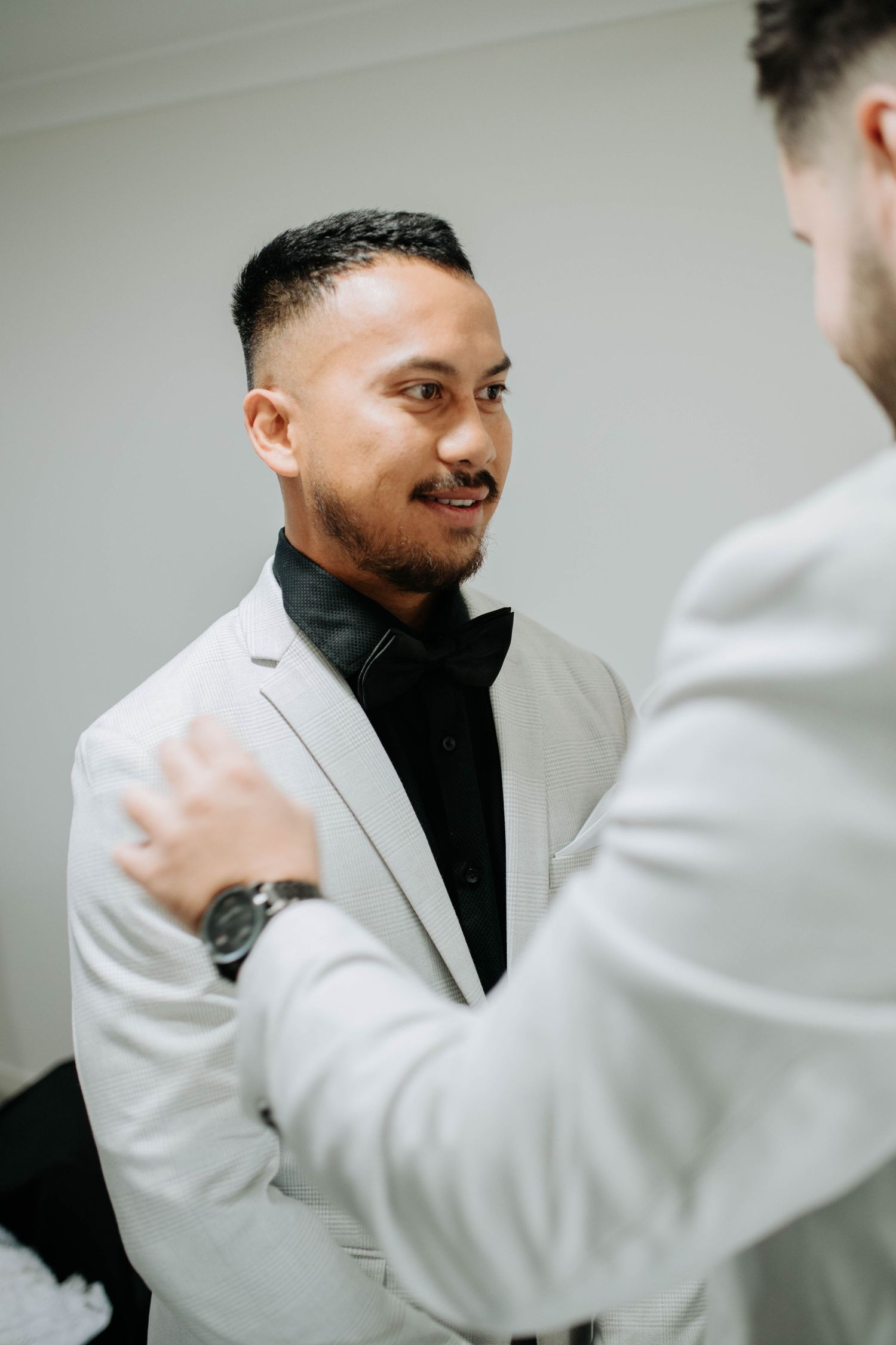 Two people in formal attire sharing a moment during wedding preparations.