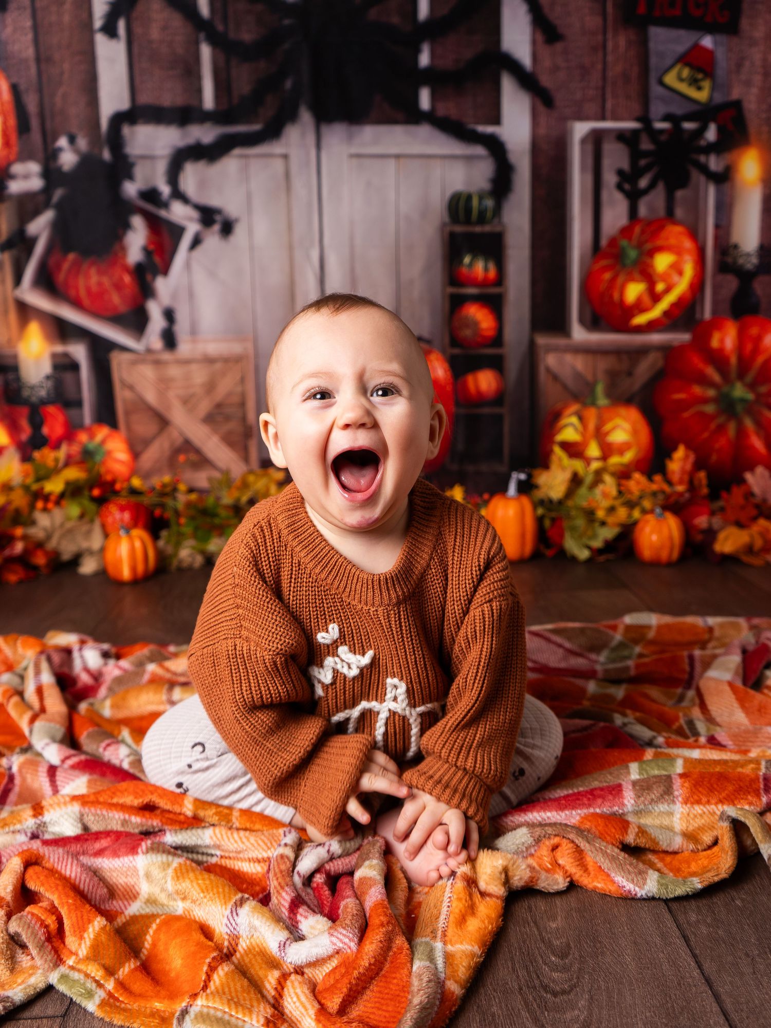 baby boy sitting and laughing at pumpkin halloween mini session in Doncaster with client of Heather Katie Photography.