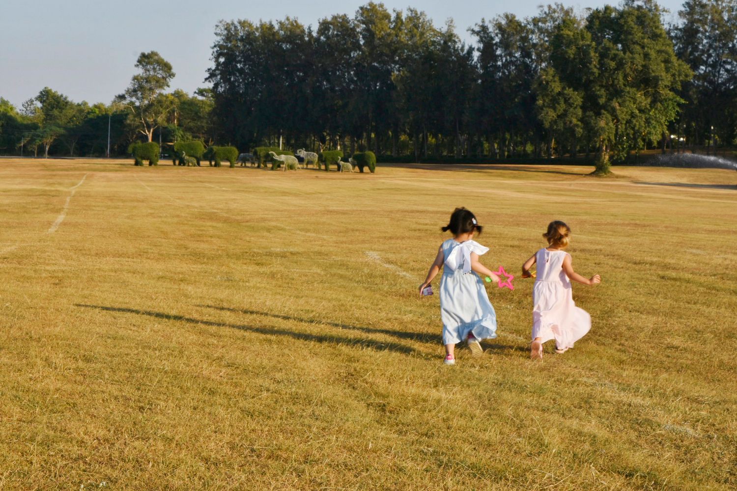 Children run across the field holding toys in their hands, Pattaya, Thailand