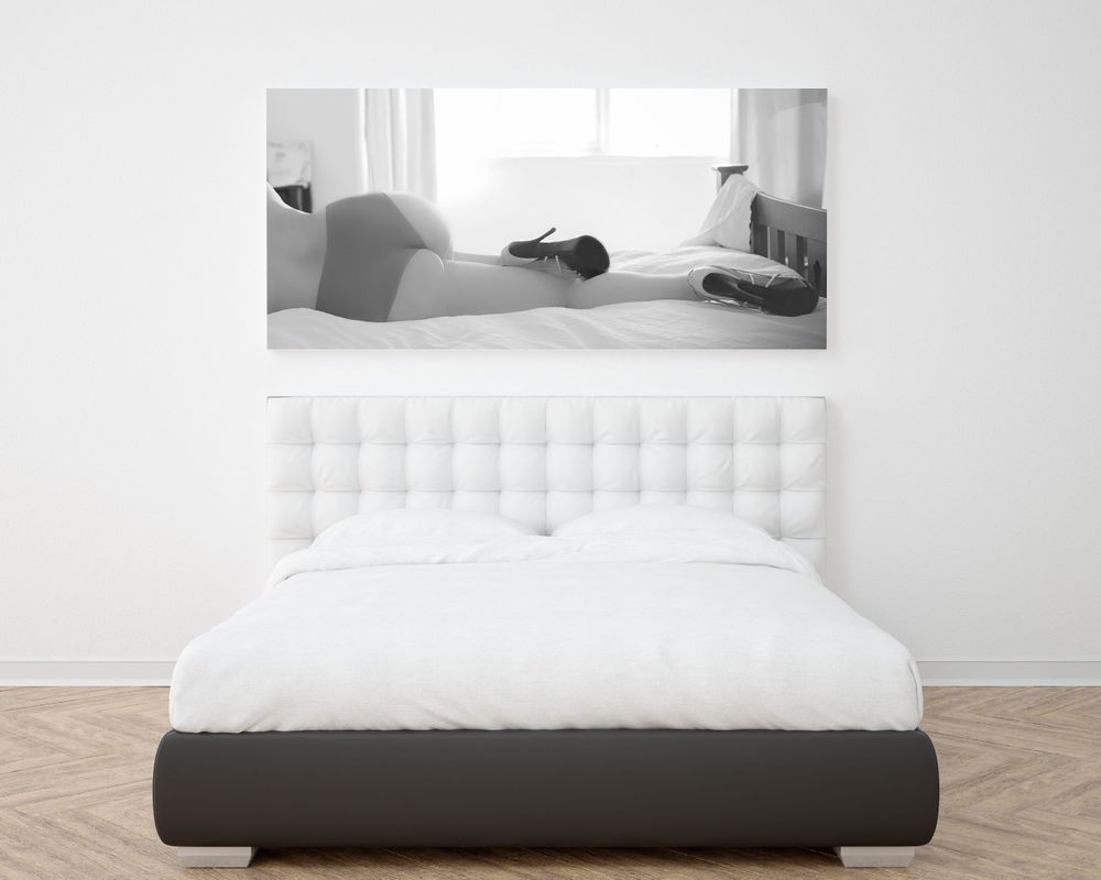 Modern bedroom interior with white tufted headboard and minimalist black and white artwork.
