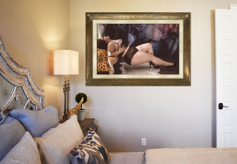 Elegant bedroom with antique headboard and framed boudoir photo on wall.