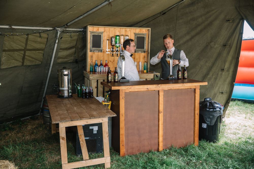 Rustic outdoor bar setup with wooden counter in festival tent.