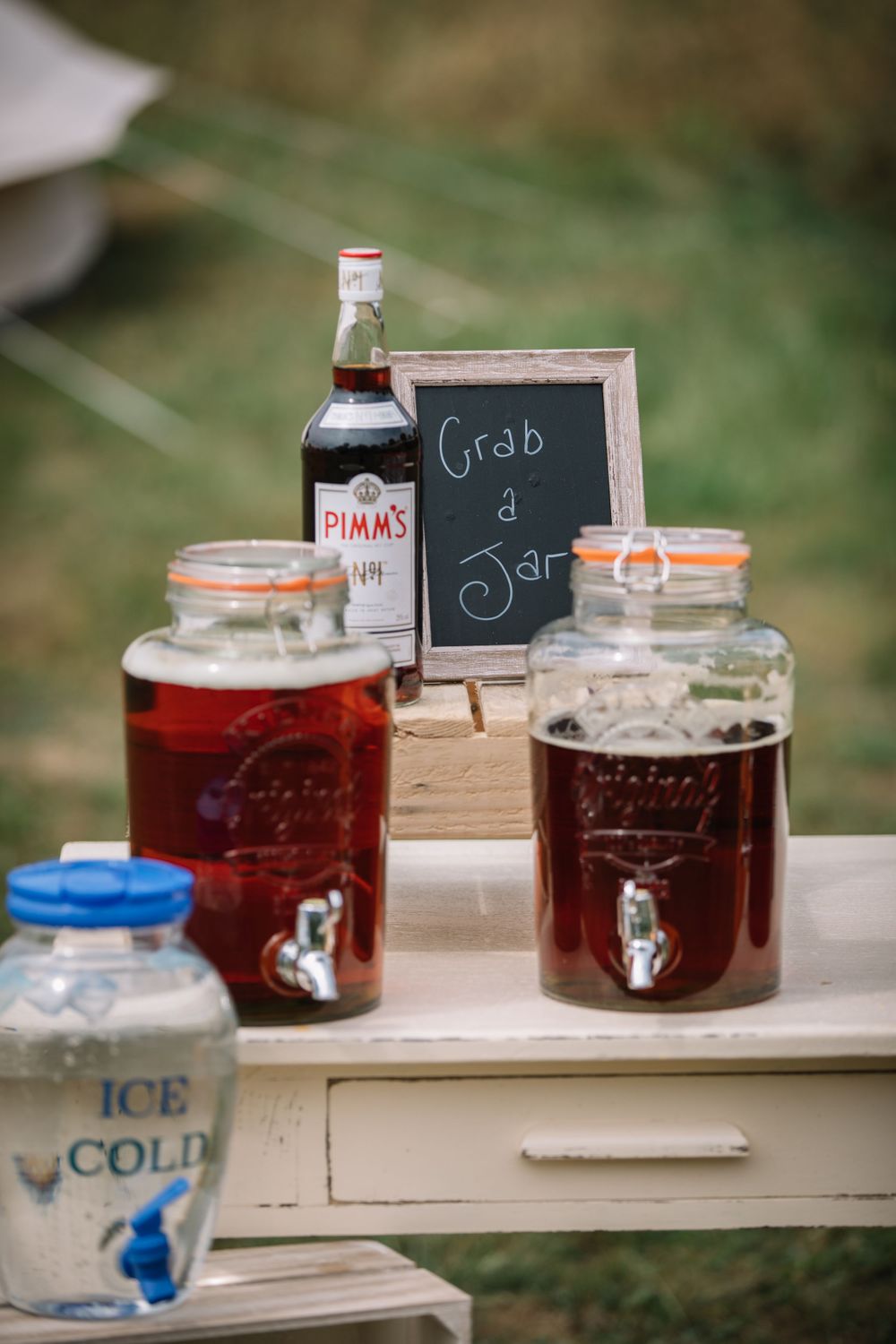 Vintage-style beverage station with mason jars and chalkboard sign for self-serve drinks.