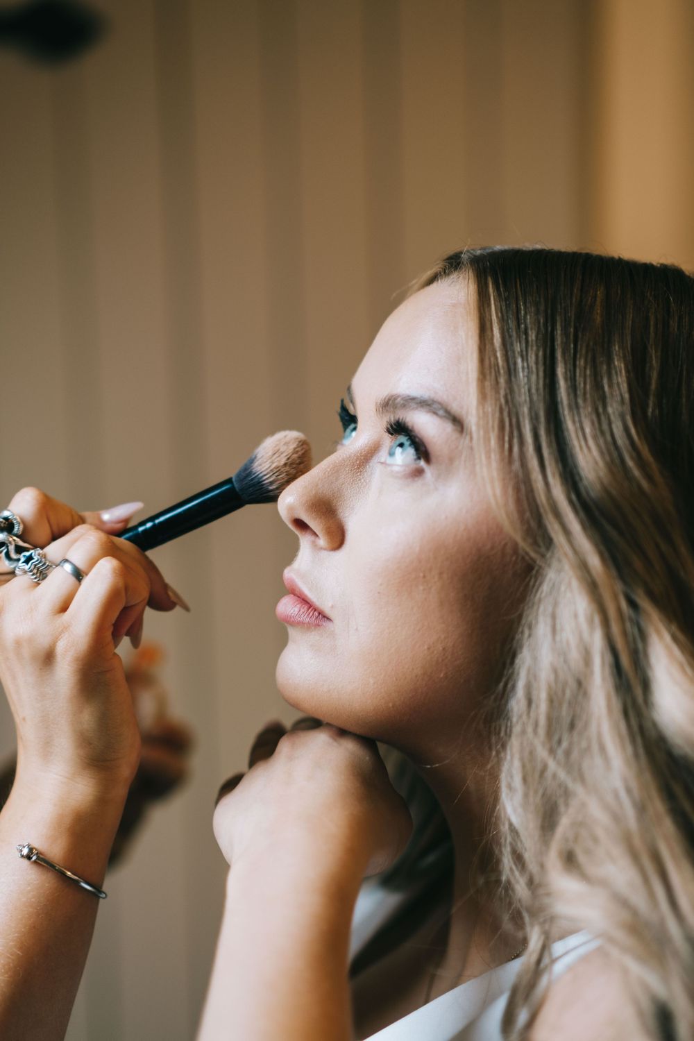 Close-up shot of makeup application with a brush during wedding preparation.