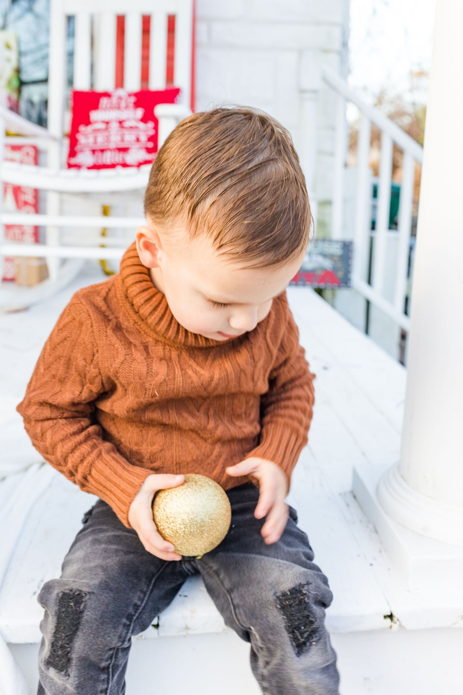 "A little boy in a cozy knit sweater, posing with holiday decorations in the scenic Hudson Valley.