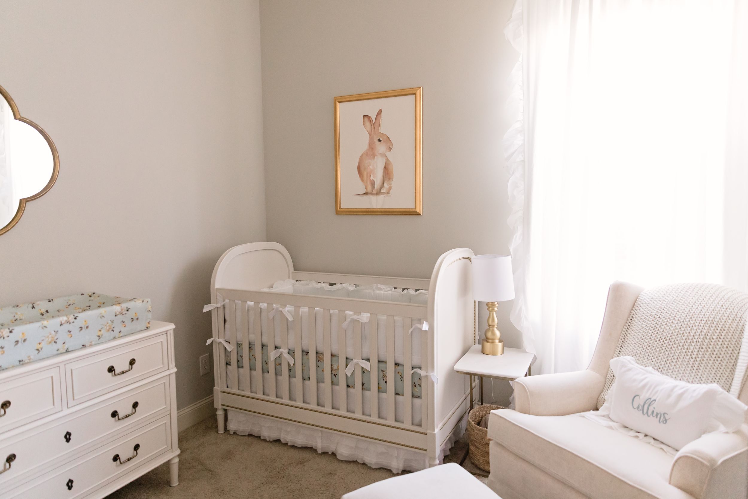 Serene neutral nursery with white crib, dresser, and bunny artwork on beige walls.