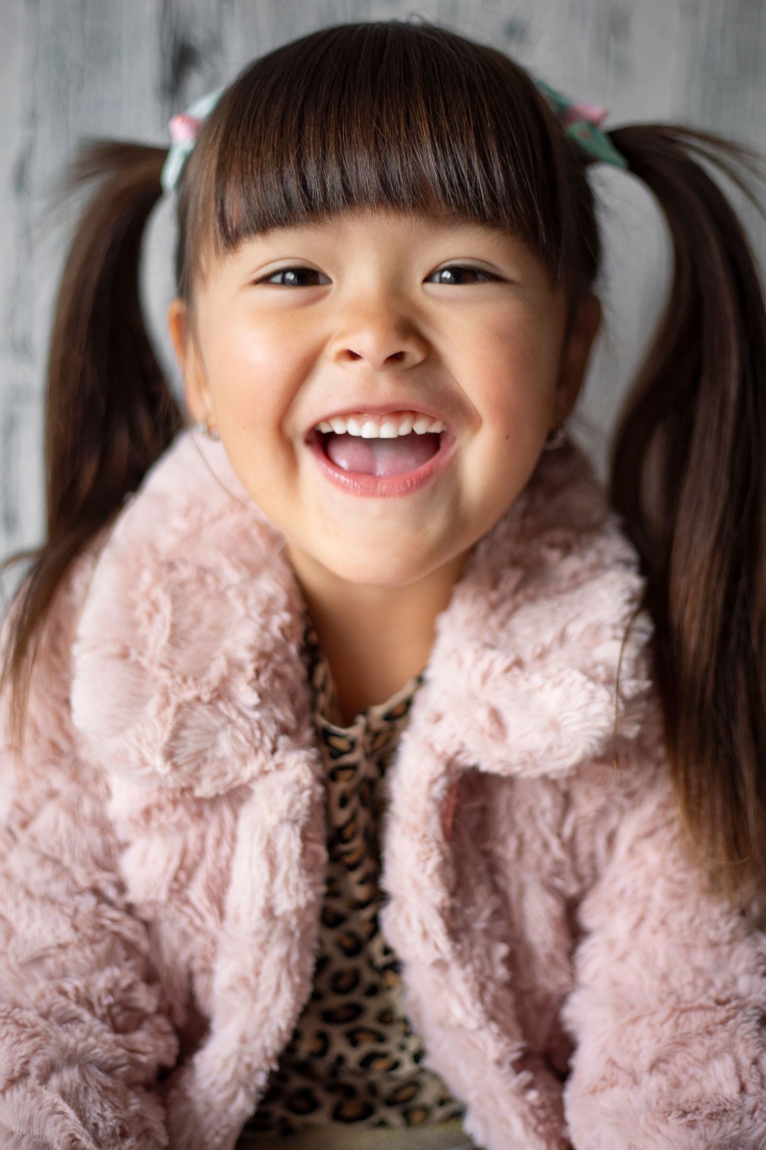 Child wearing pink fur coat and leopard print top smiling in progression of photos.