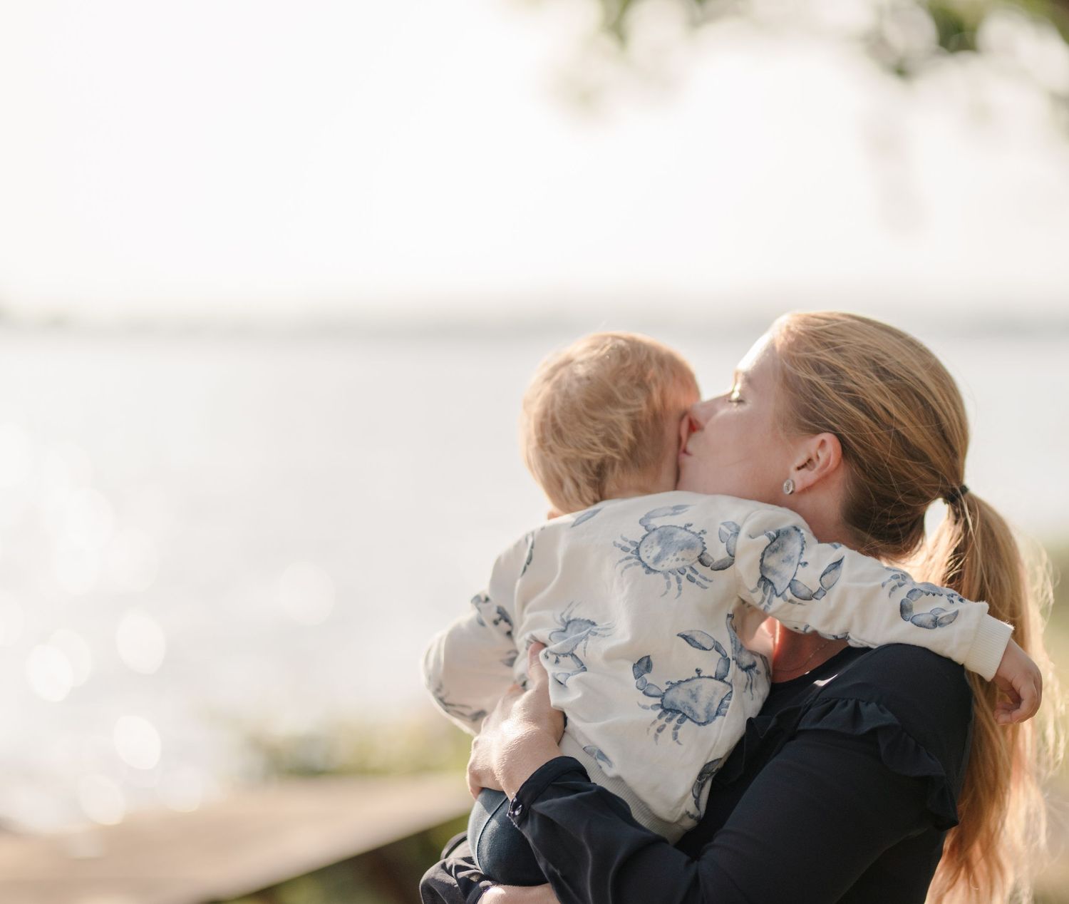 Tender moment shared between people at the waterfront with soft lighting.