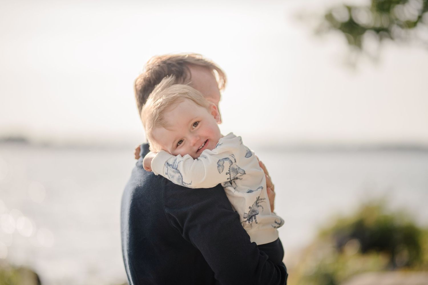 Sweet embrace captured in soft natural lighting by the waterfront.