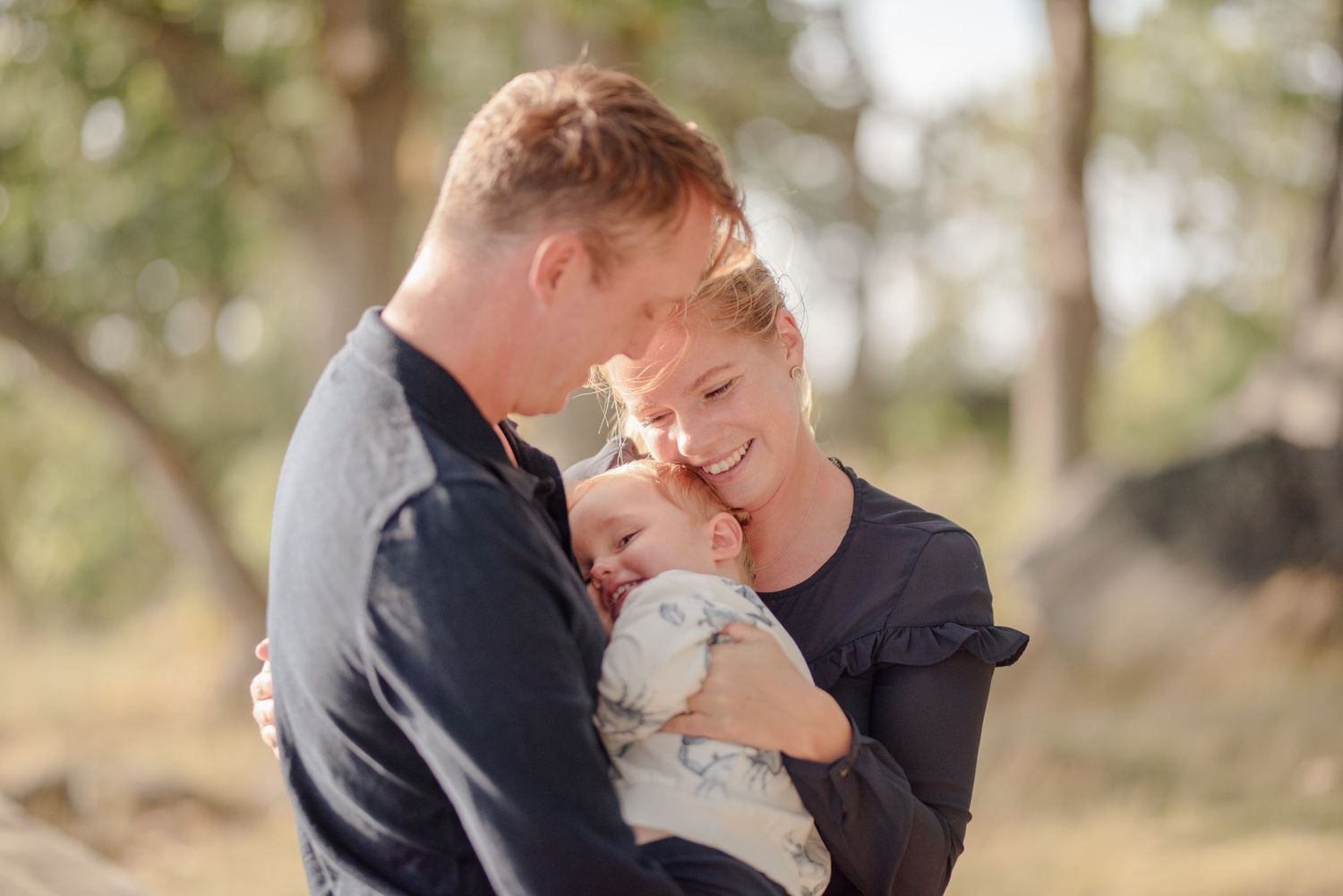 Tender family moment shared on a sunny day by the coast.