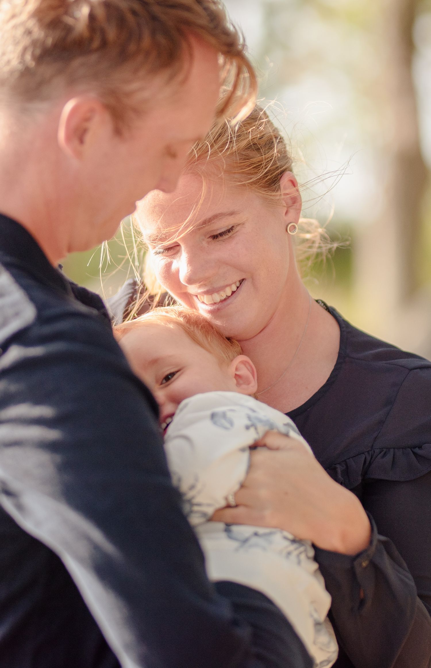 Intimate family moment captured in warm sunlight by the water.