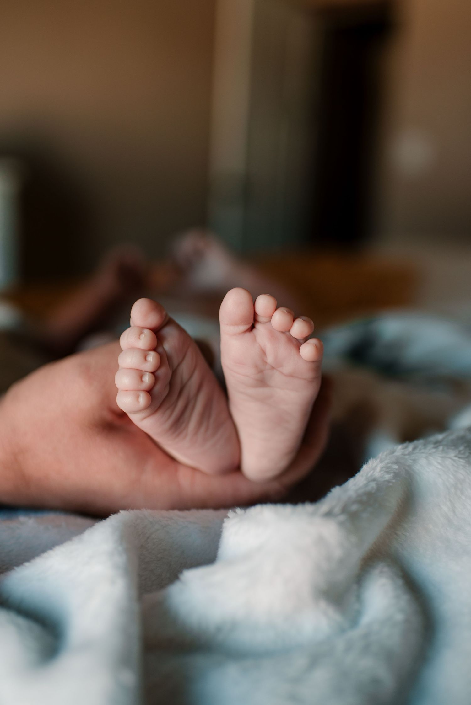 Close-up of tiny baby feet resting on soft white blanket.