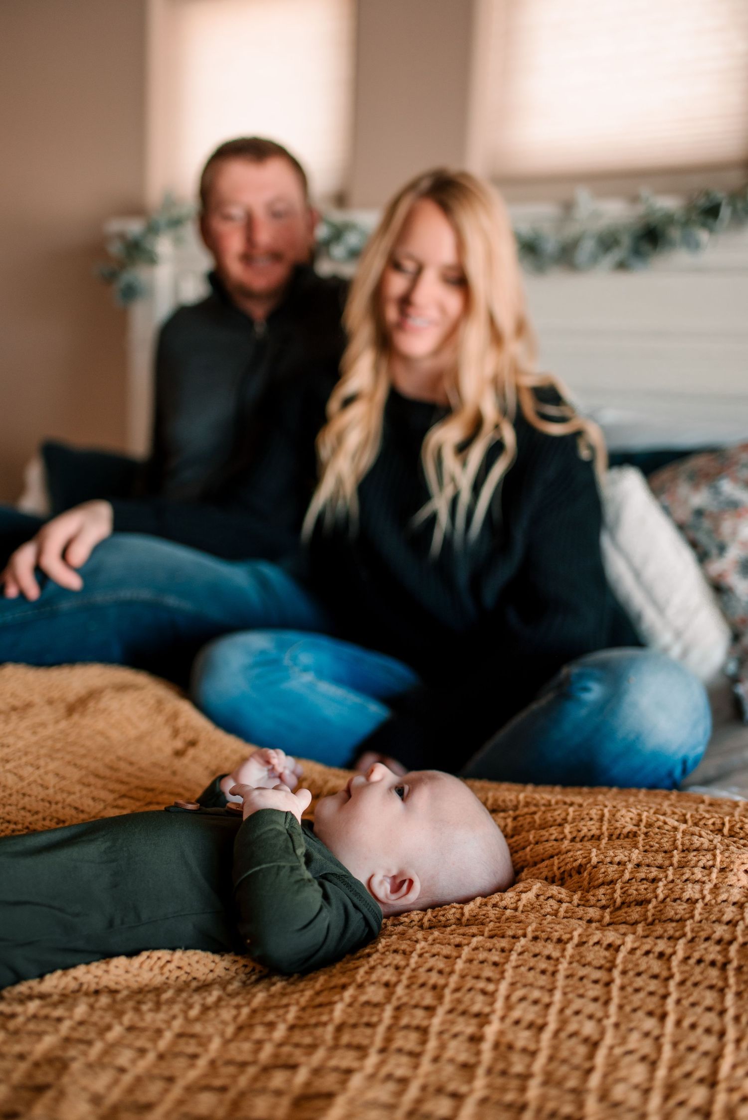 Family relaxing together on a textured beige blanket during an intimate indoor photoshoot.