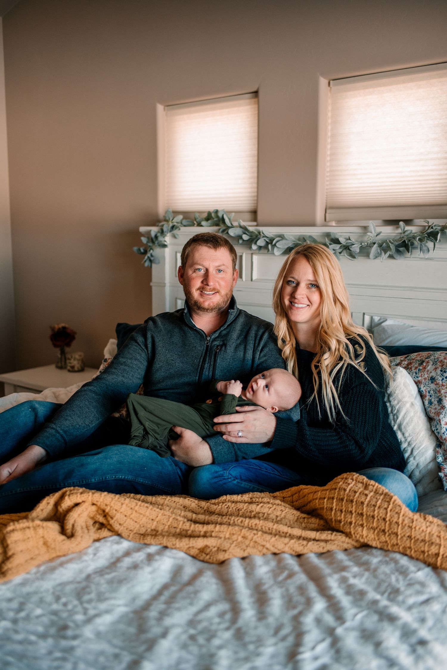Family lounging together on bed with cozy blanket during lifestyle photoshoot.