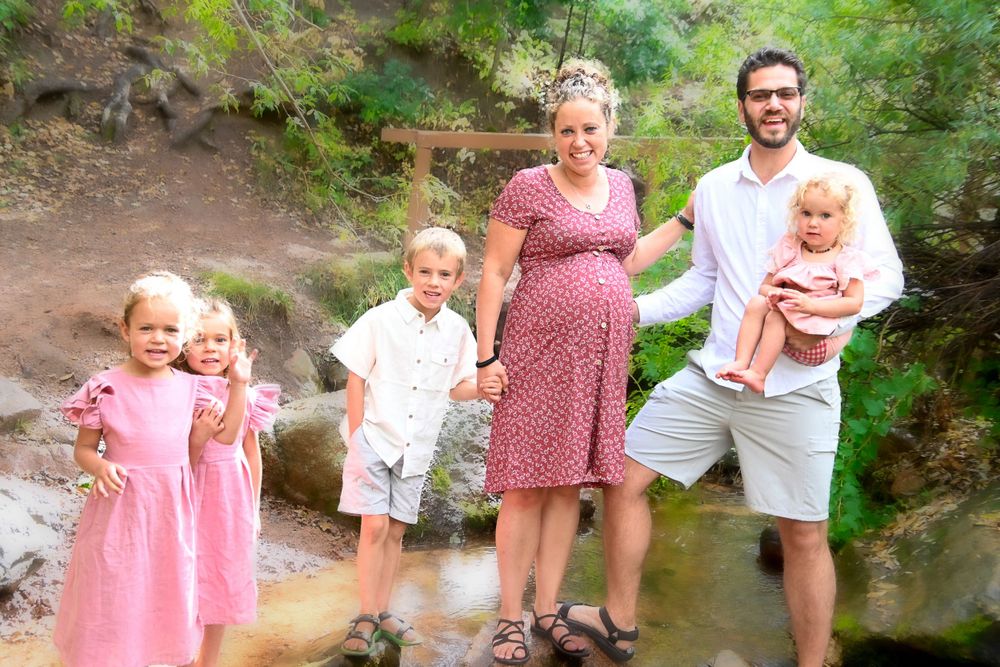 Family enjoying a sunny day together outdoors near a stream.