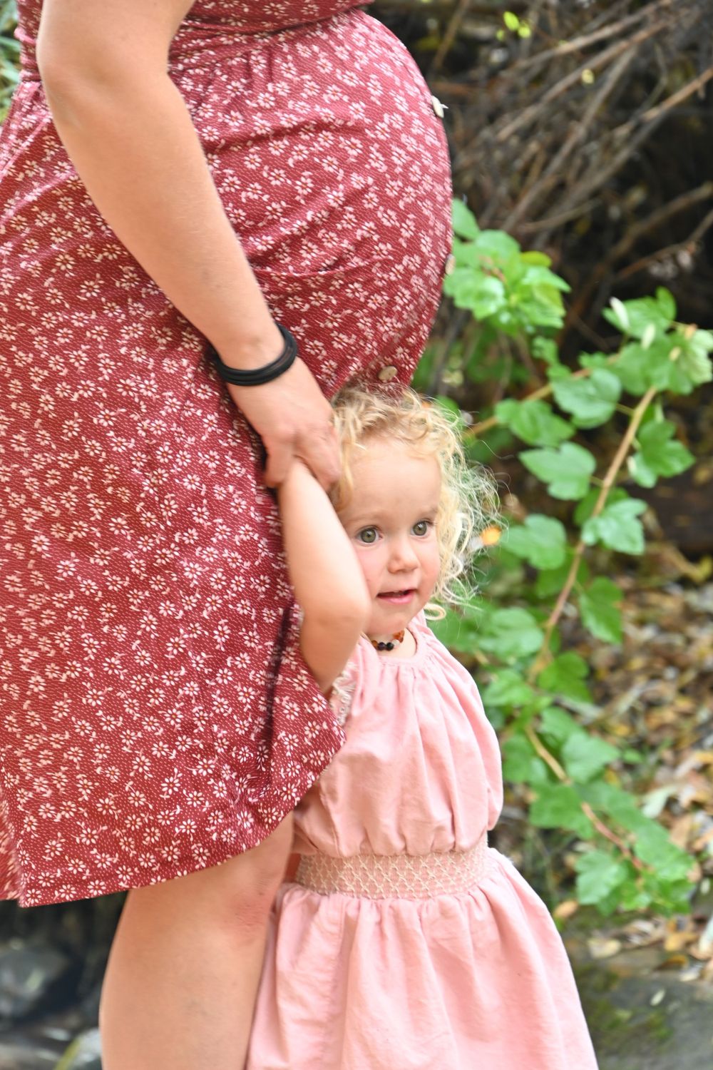 Close-up view of a red floral dress against a green outdoor background.