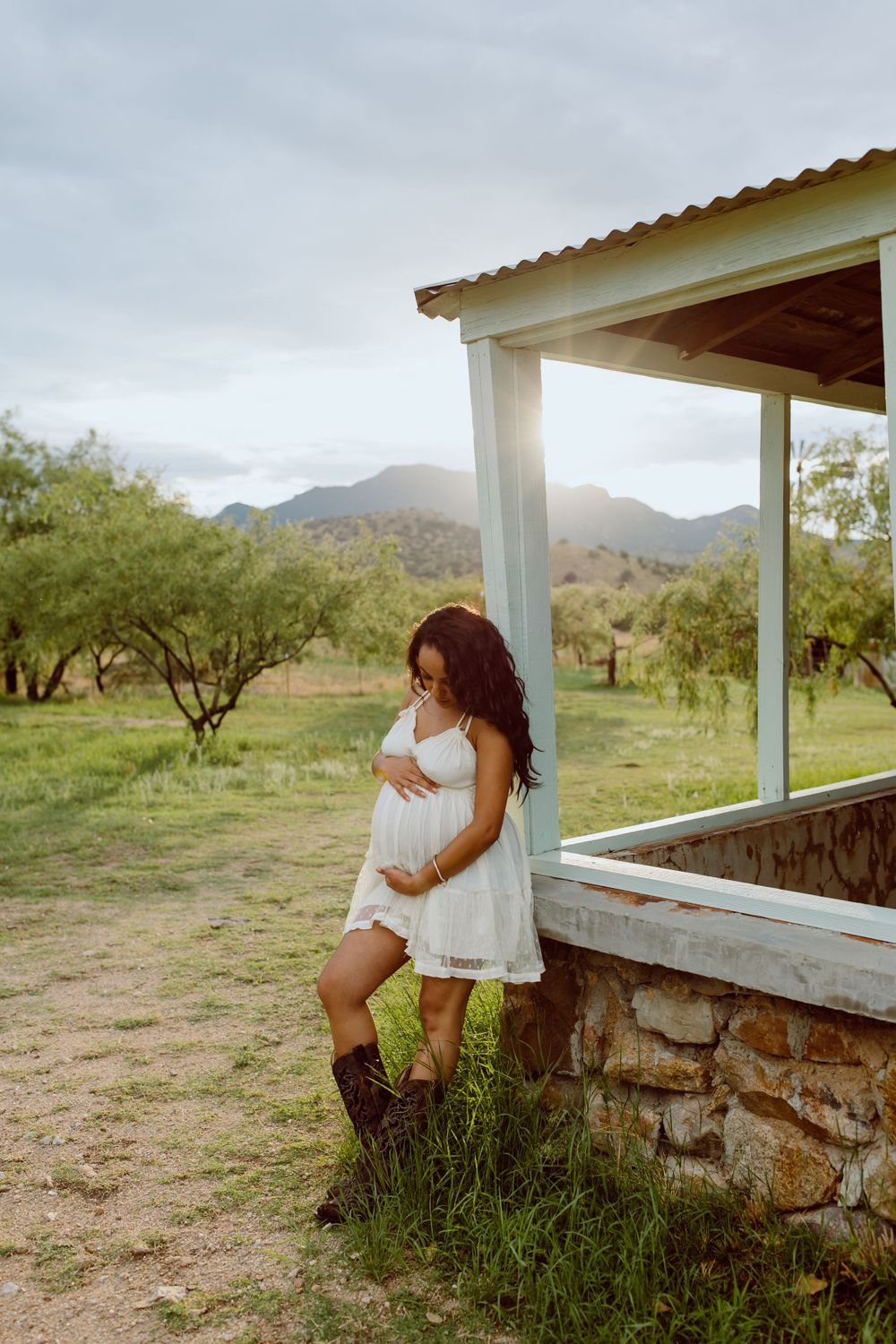 A rustic porch overlooks a desert landscape with mountains in the background.