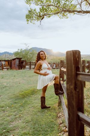 Old wooden corral fencing stands against a backdrop of mountains and cloudy skies.