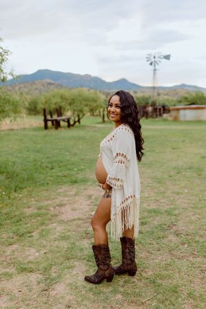 Brown leather boots contrast with green grass in a mountain ranch setting.