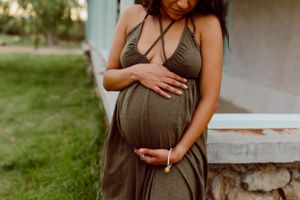 An olive green dress is photographed against a rustic porch setting.