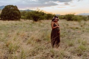 Desert maternity session with golden light and mountains in the distance.