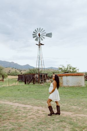 A vintage windmill stands tall in a desert ranch setting.