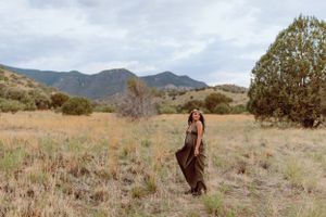 Scenic desert maternity photos with mountains and brush in the background.