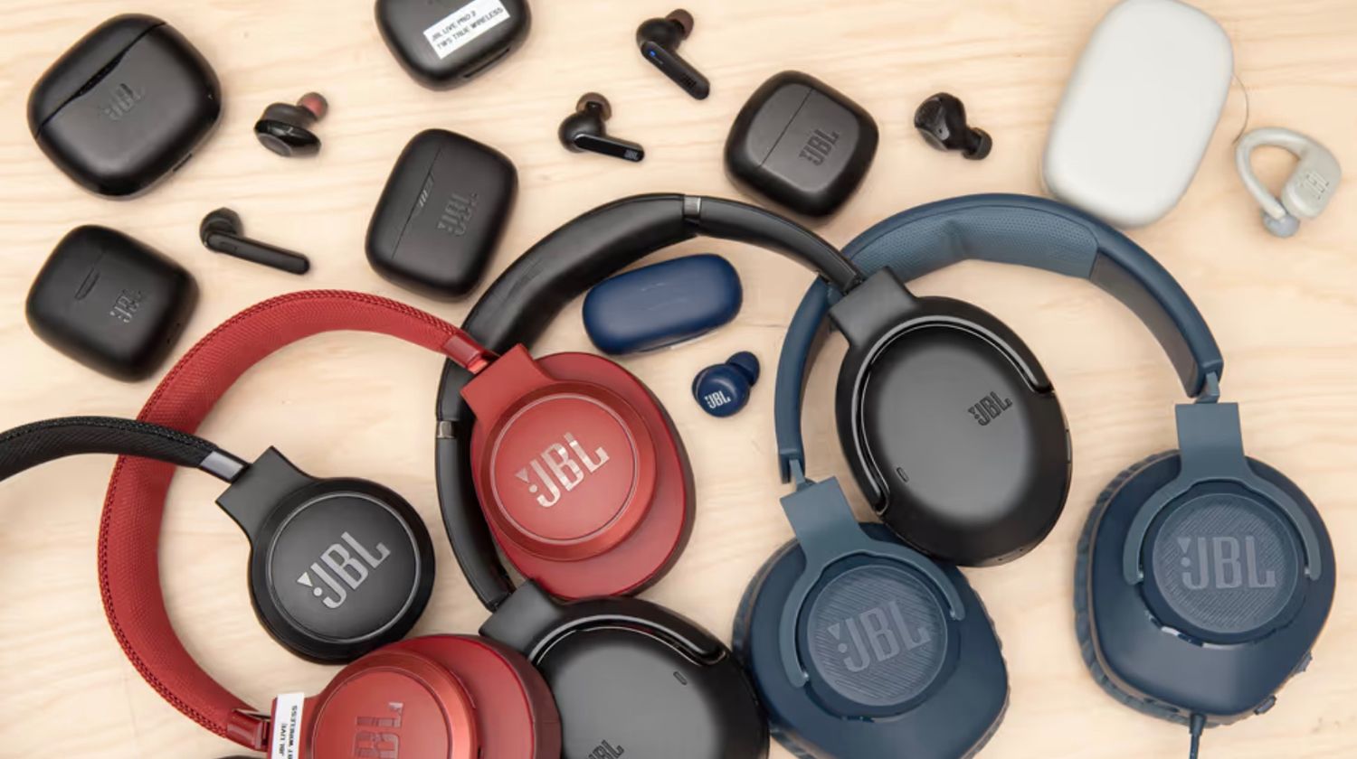 Collection of JBL wireless headphones in various colors displayed on wooden surface.