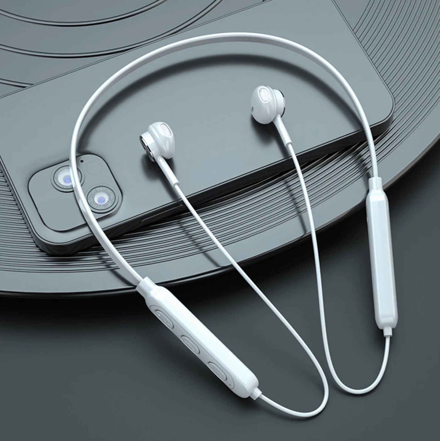 White neckband wireless earbuds displayed on gray textured surface with smartphone.
