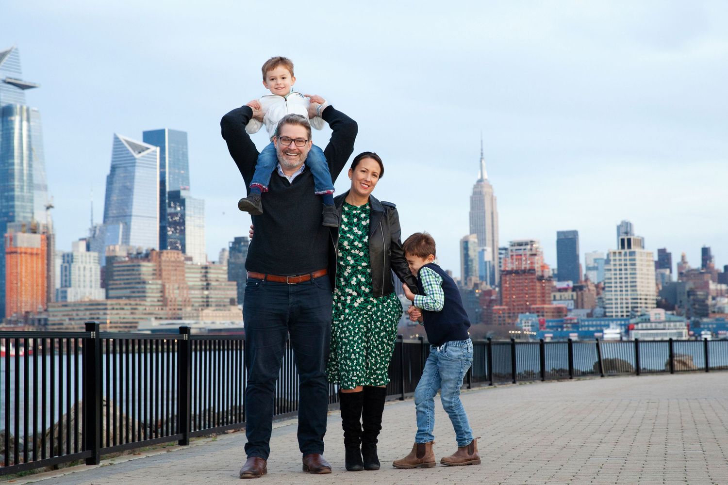 Happy family poses together against Manhattan skyline backdrop.