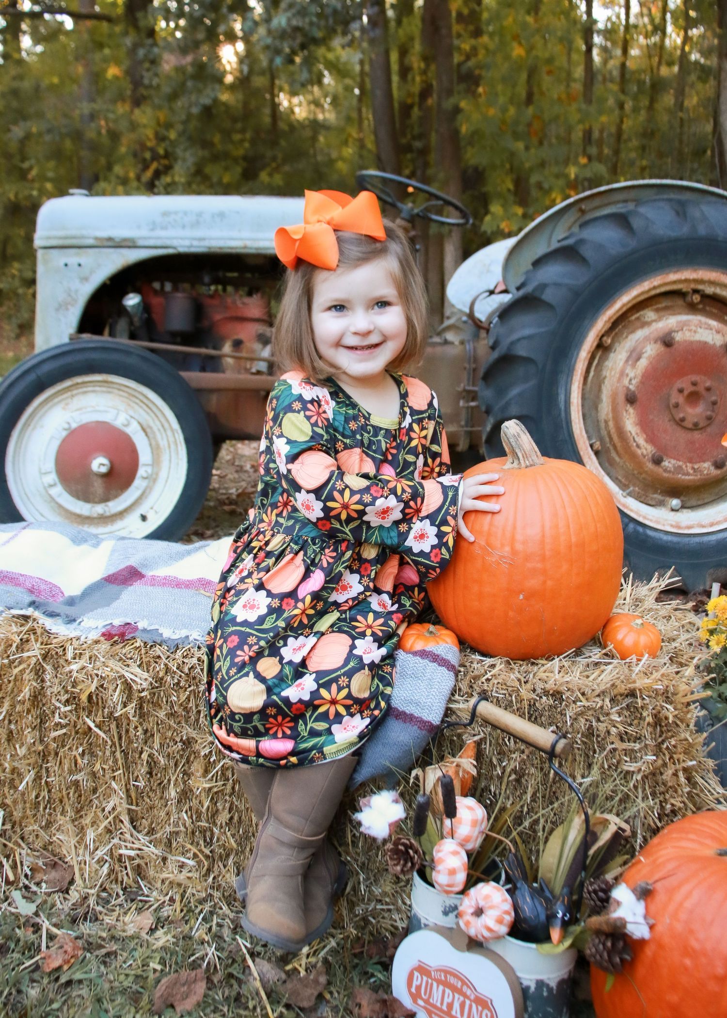Autumn scene at pumpkin patch with decorative hay bales and orange pumpkins.
