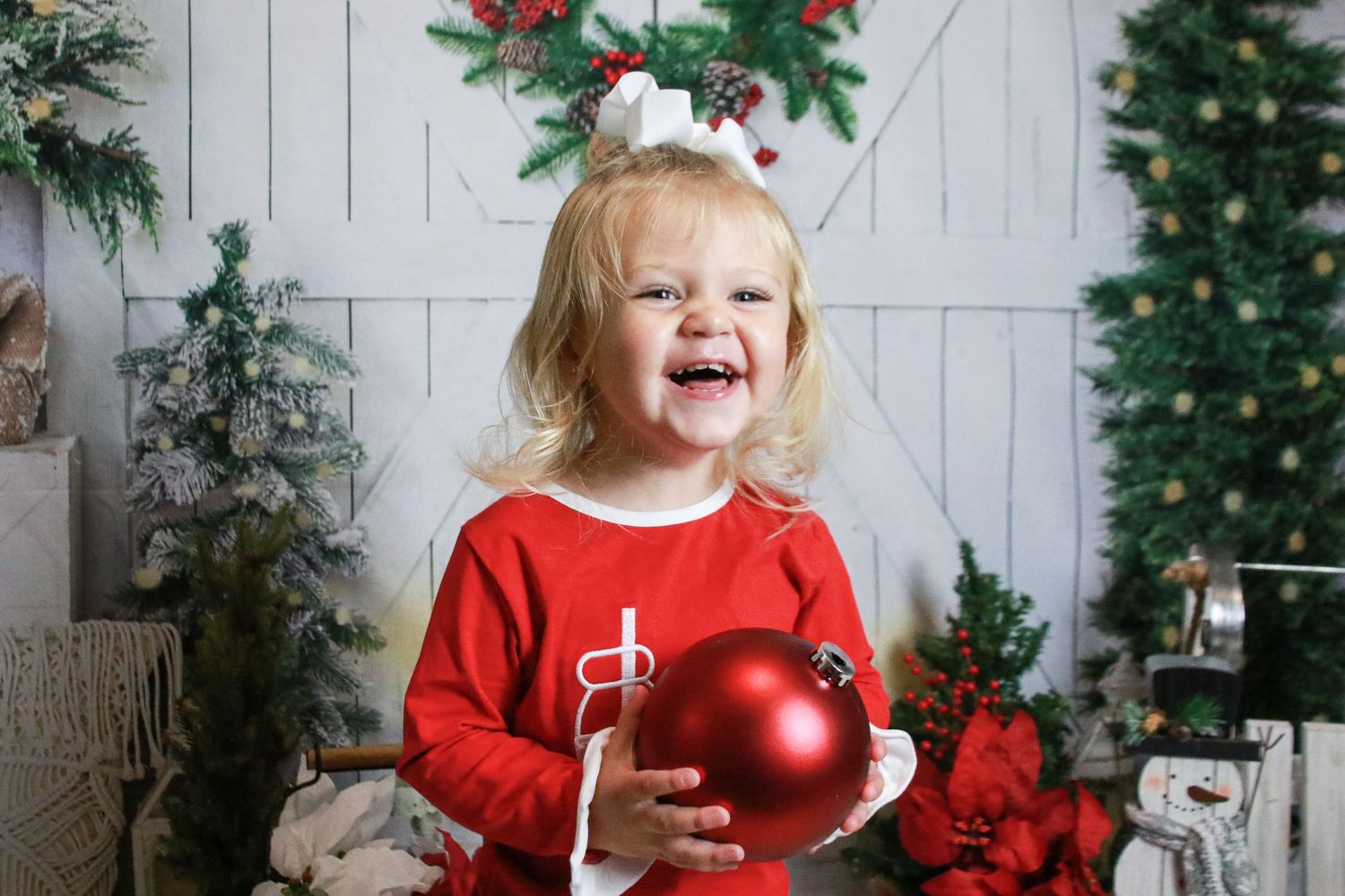 Christmas themed photo setup with white barn doors, wreaths and red ornament.