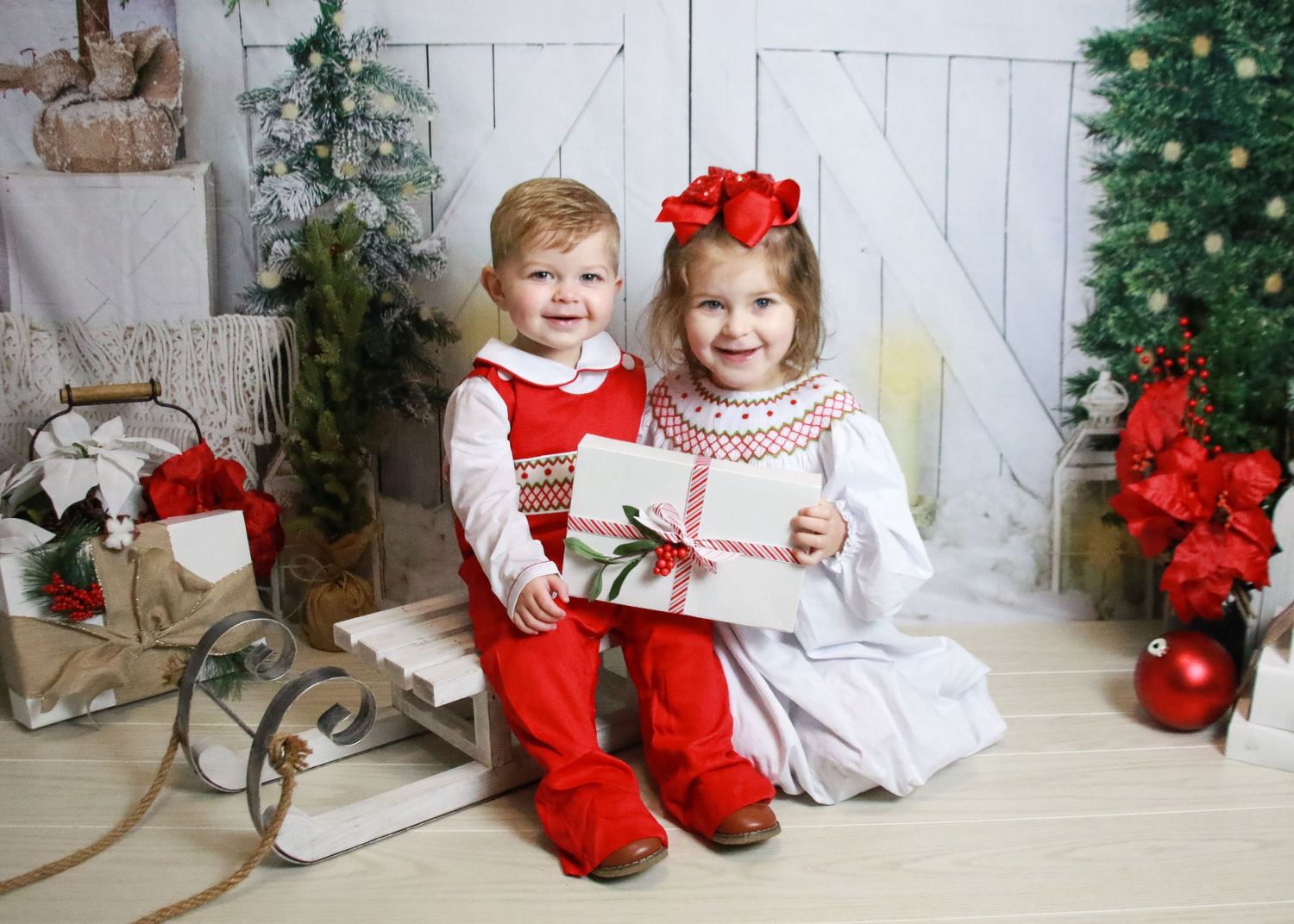 Holiday photo setup with rustic sleigh, Christmas trees and festive decorations.