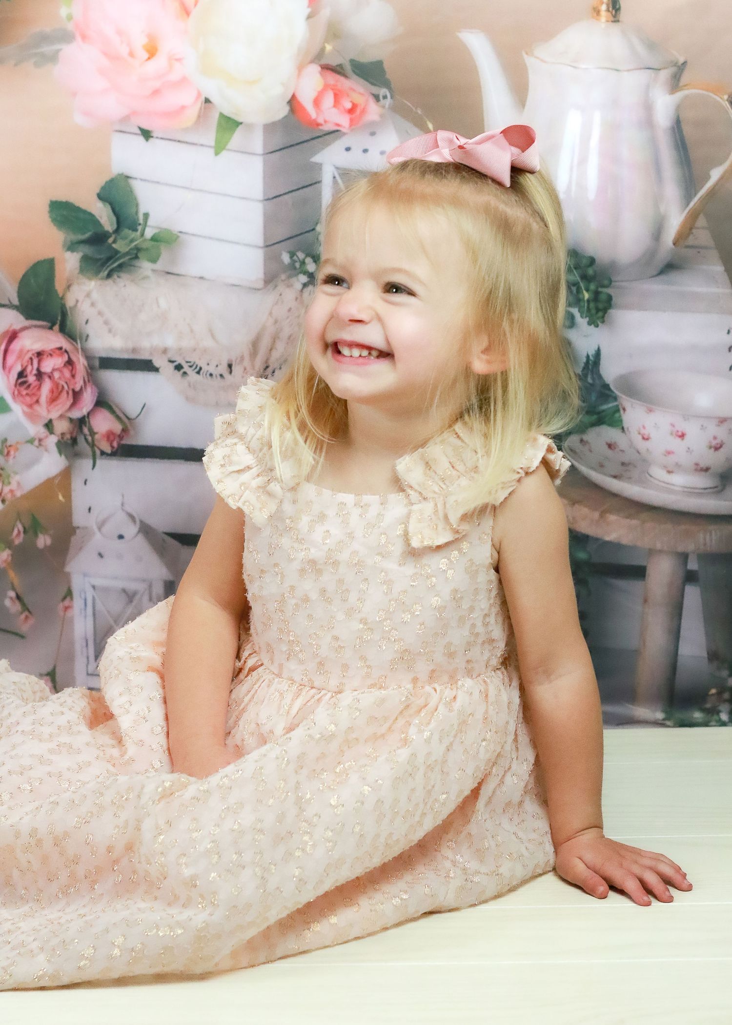 Tea party themed photo setup with pink roses, white boxes and vintage teapot.