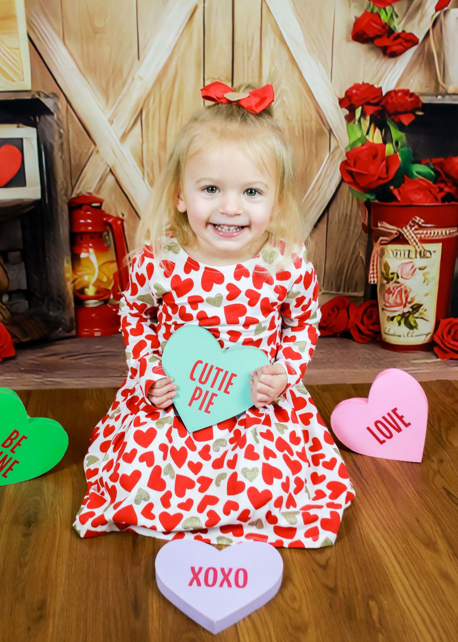 Valentine's Day themed photo with red roses, heart decorations, and wooden barn door background.