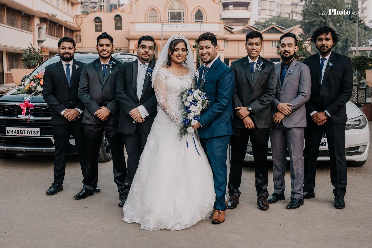 Wedding party in formal attire poses together outdoors.