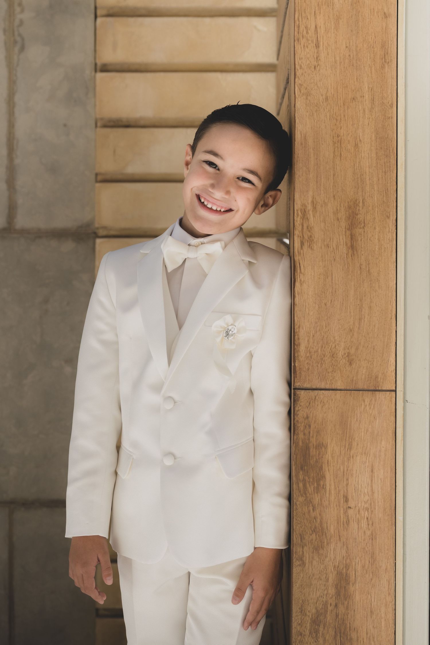 A person in a white suit smiles brightly while standing in a doorway.