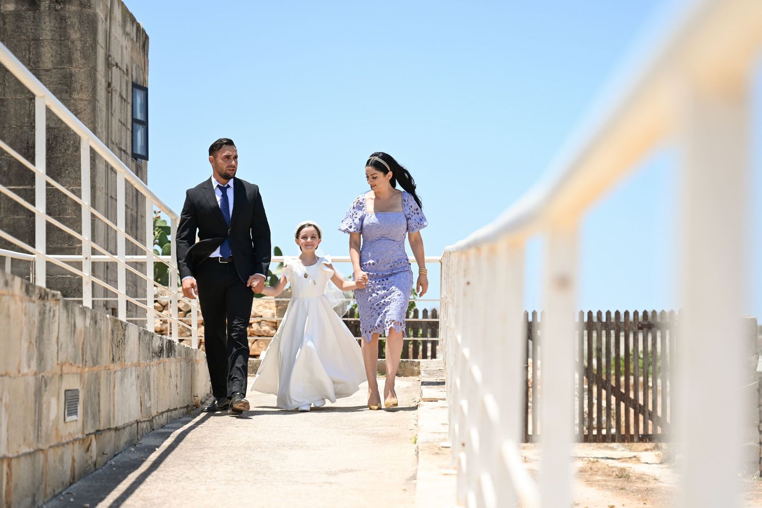 People gather on a sunlit stone pathway for formal event photography.