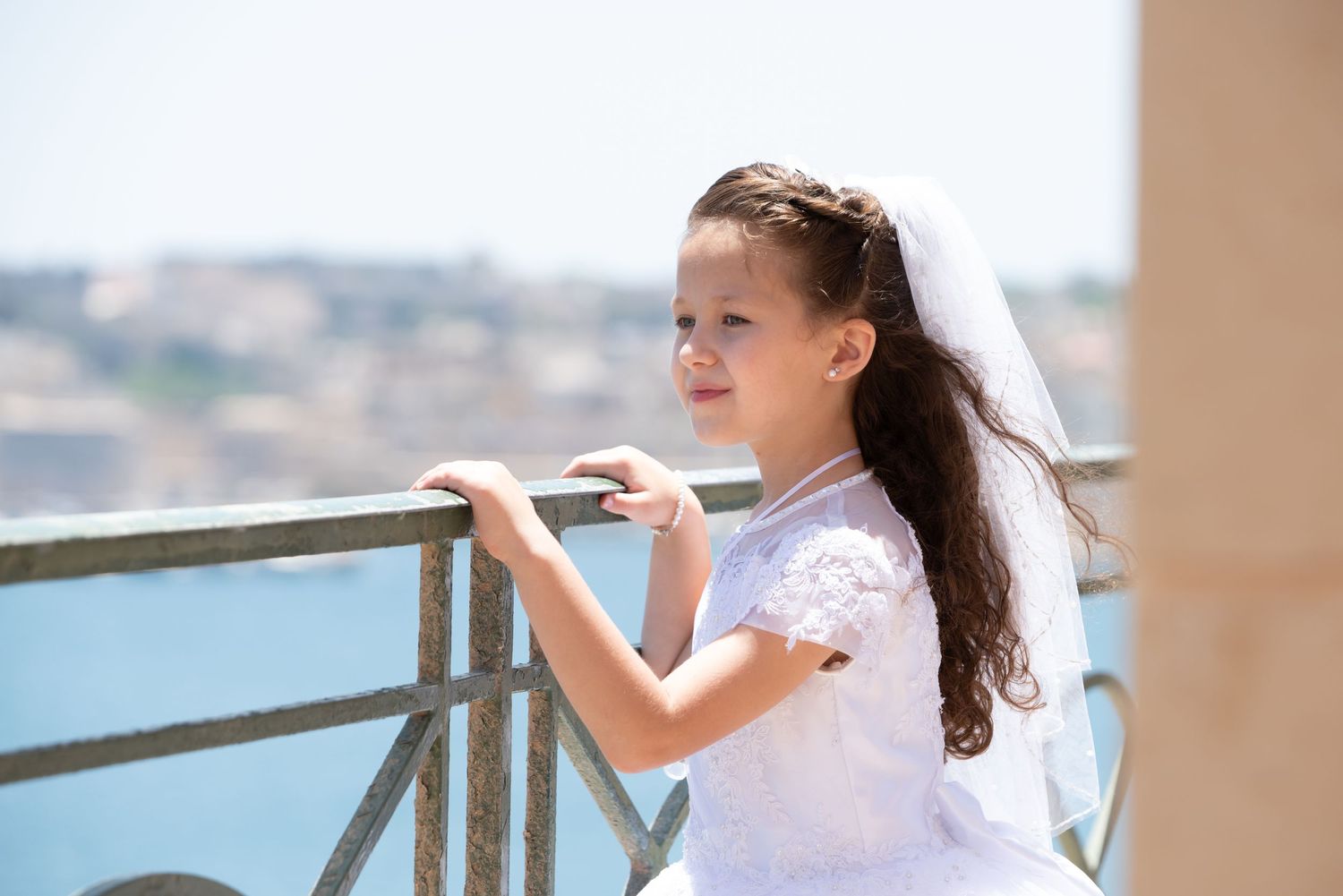 A white dress captured in motion against a coastal balcony view.