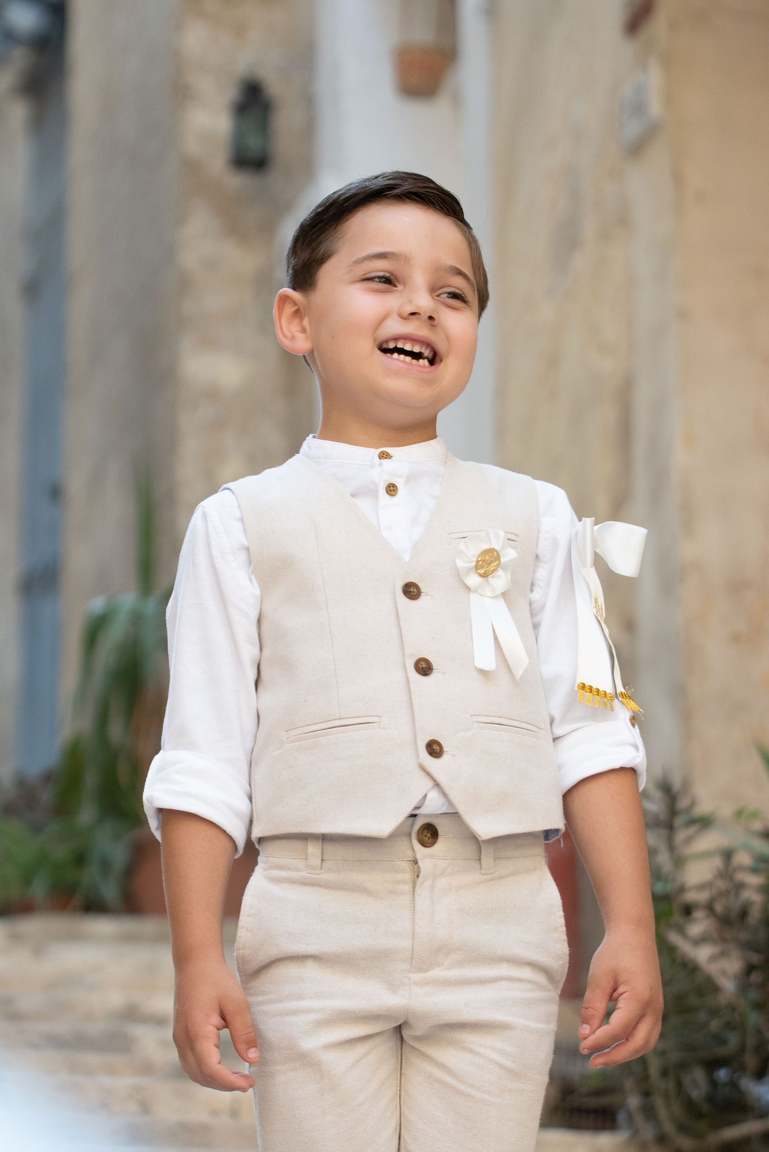 Young child wearing a cream-colored vest and shorts ensemble smiling in multiple poses.