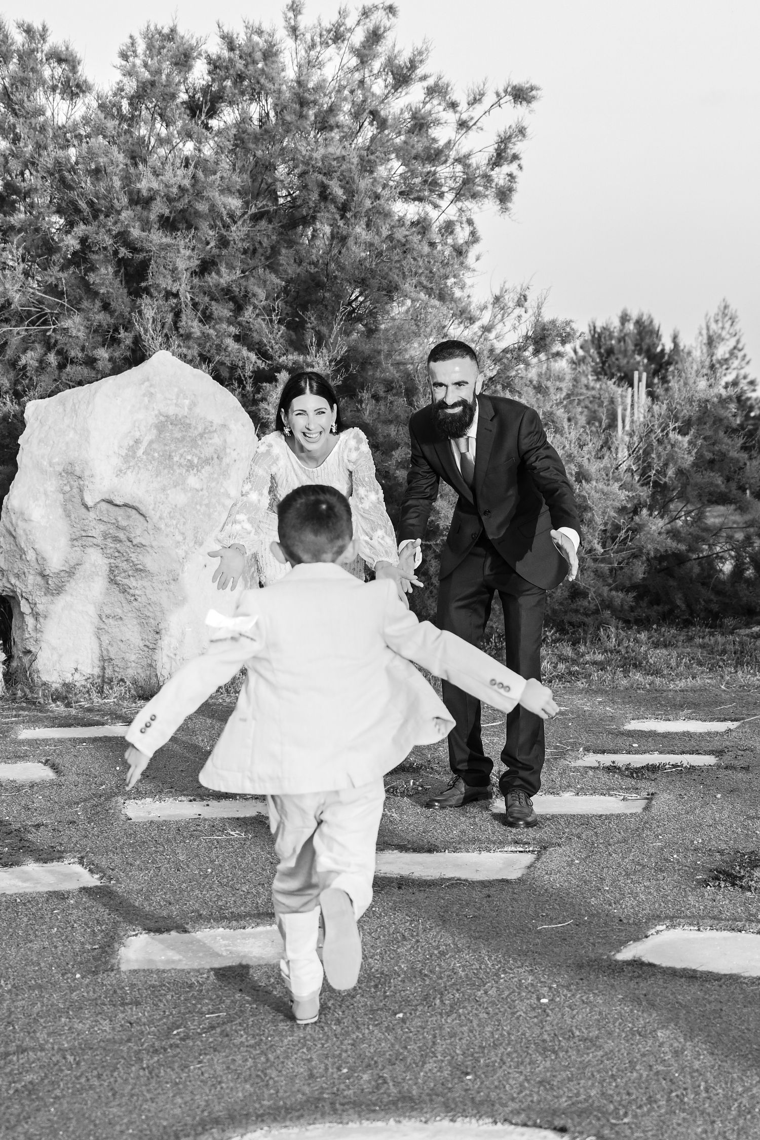 A joyful black and white photo of a family moment in a garden setting.