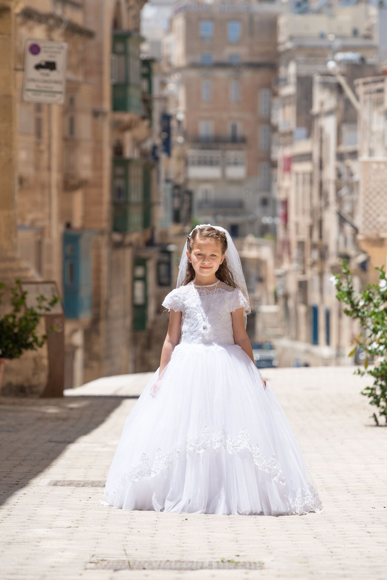 An elegant white dress captured in multiple frames along a sunlit Mediterranean street.