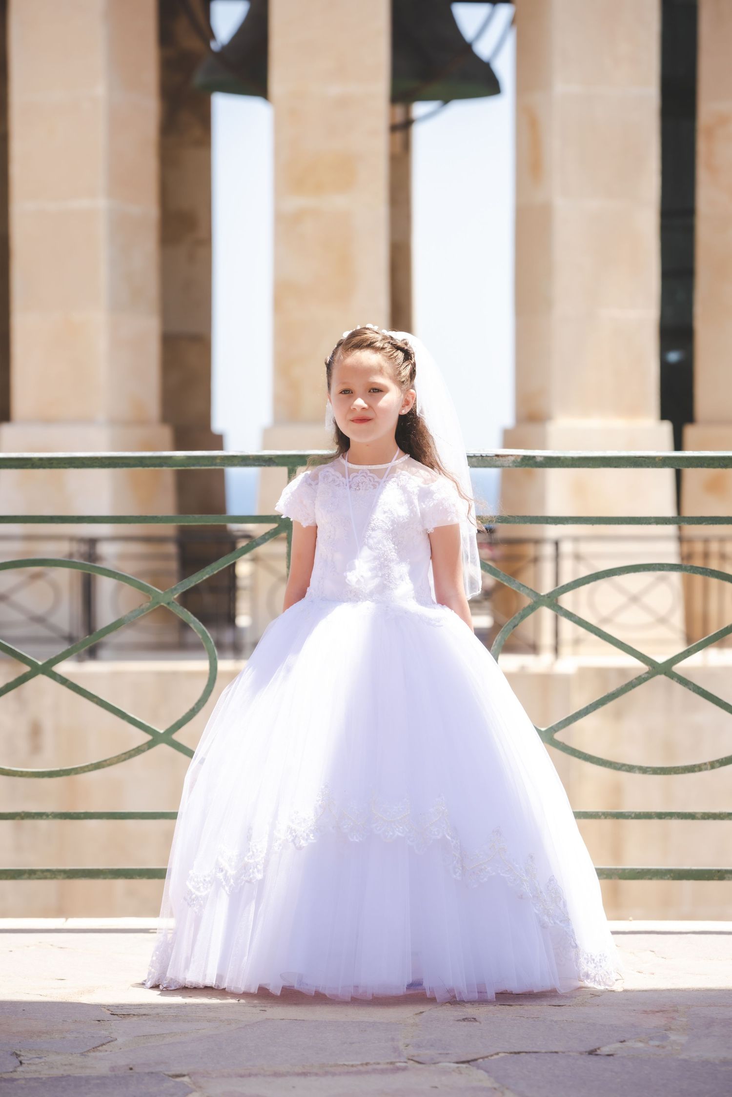 A series of photos showing a flowing white formal dress with delicate lace details in an elegant outdoor setting.