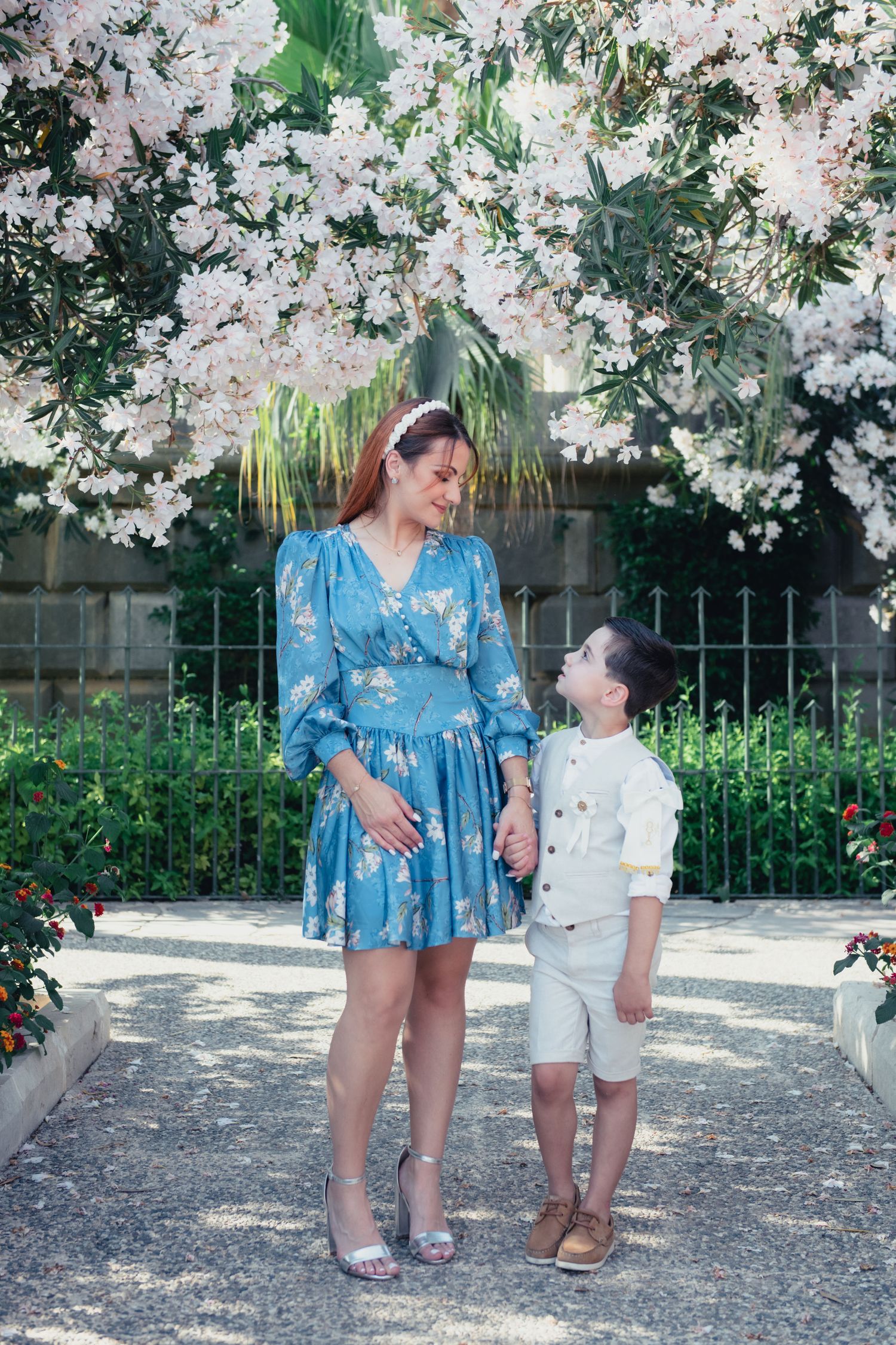 Spring photoshoot under blooming white cherry blossoms with blue and cream outfits.