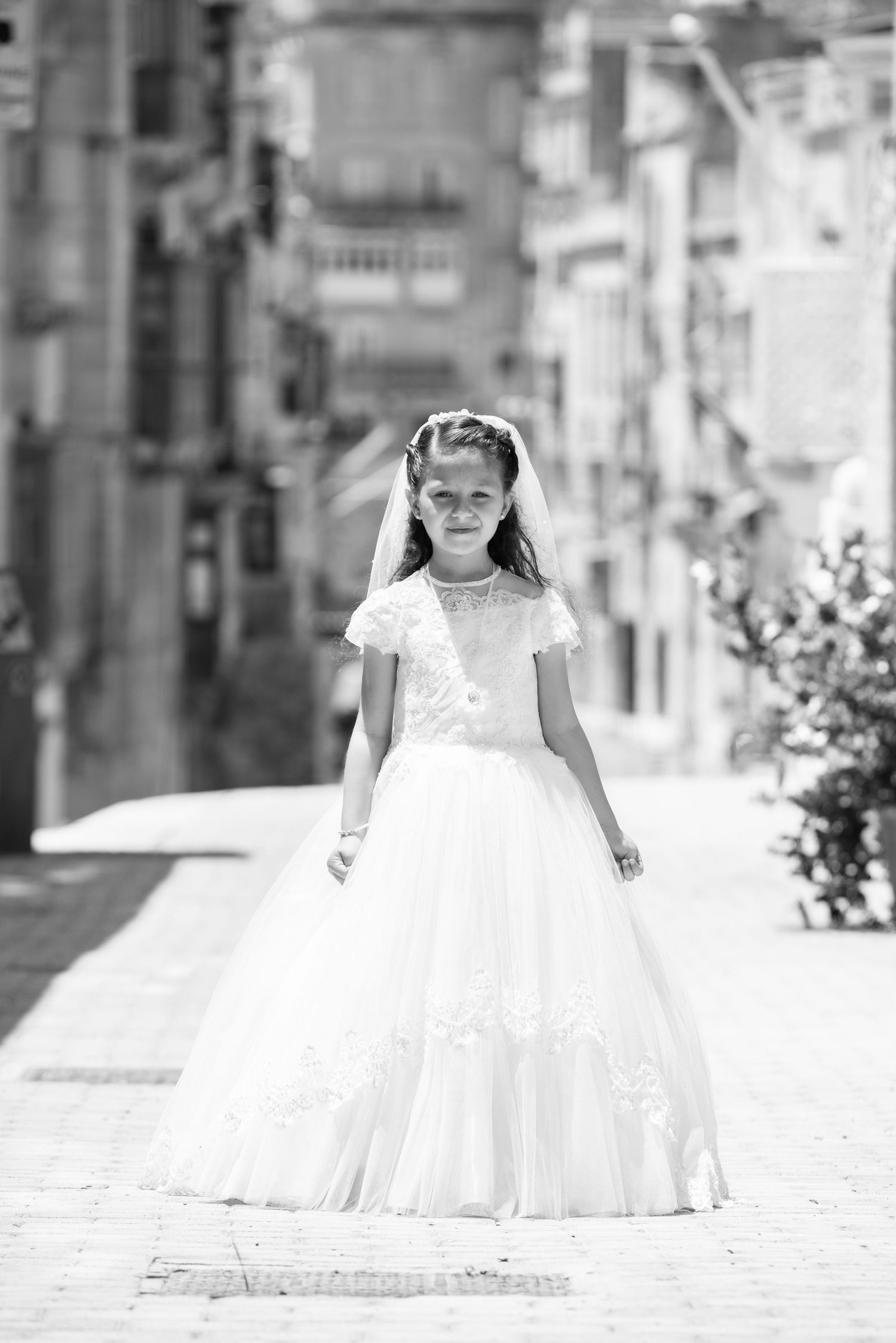 A white formal dress photographed in black and white against an urban backdrop.